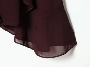 Détail de l'ourlet à volants avec couture overlock sur haut en mousseline bordeaux