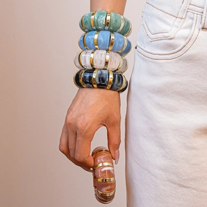 Close-up of colorful acrylic bangles with gold metal spacers worn on a female wrist