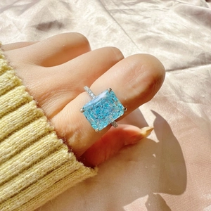 Close-up of S925 sterling silver ring with emerald-cut light blue zircon on beige silk