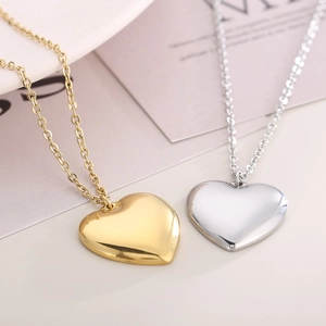 Detail view of heart-shaped gold and silver stainless steel necklaces on a white plate