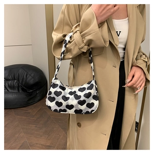 Détail d'un sac sous le bras en toile chic avec motifs de cœurs noirs et blancs