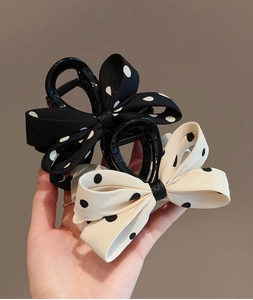 Vue détaillée des pinces à cheveux à nœud à pois en tissu noir et crème élégant