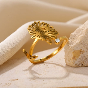 Macro shot of gold sunflower ring with zircon on a textured stone display base