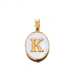 Macro shot of oval stainless steel pendant with gold letter K and mother of pearl inlay