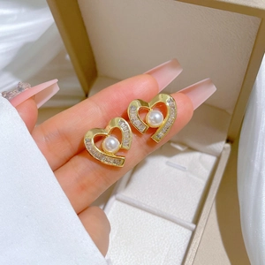 Detailed view of heart-shaped pearl earrings with gold metal and zircon stones