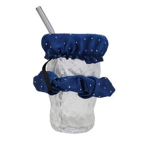 Close-up of blue drink cover scrunchie with silver dots on a glass with straw