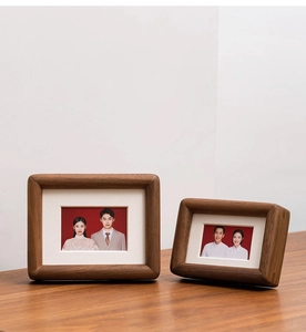 Macro detail of two black walnut wood magnetic photo frames with natural wood grain