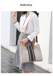Model wearing striped canvas tote bag with brown leather handles and adjustable strap