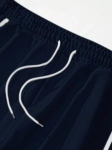 Detail of navy blue joggers showing elastic waistband with white drawstrings and side stripes