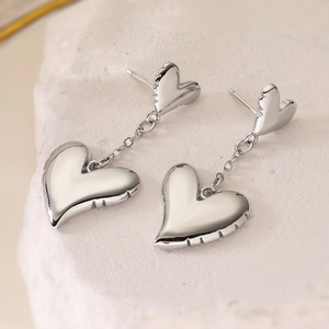 Elegant silver heart drop earrings with ribbed texture on stone surface