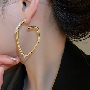 Macro shot of gold bamboo texture earrings with sparkling diamond accents on model