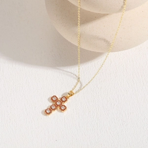 Detail of 14K gold plated cross pendant with red zircon and clear diamond inlay
