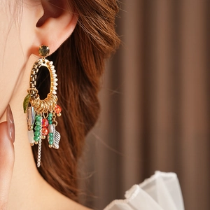 Detailed close-up of a vintage gold leaf earring with colorful beads on a female model