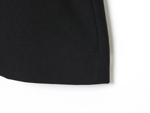 Dettaglio macro della trama del tessuto twill nero e delle cuciture precise della spalla