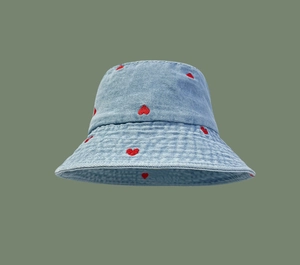 Close-up of red heart embroidery on light blue denim bucket hat with twill texture