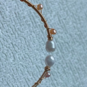 Macro detail of handmade gold wire wrapping with freshwater pearls and baroque beads