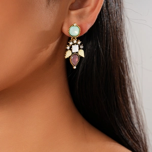 Close-up of a vintage-style earring with colorful crystals and rhinestones on a model