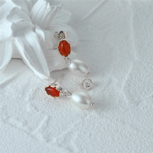 Macro detail of S925 silver earring with oval red agate and freshwater pearl drop