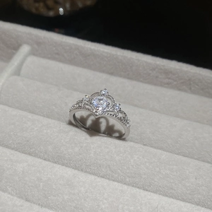 Macro detail of royal silver crown ring with sparkling zircon stones on a gray tray
