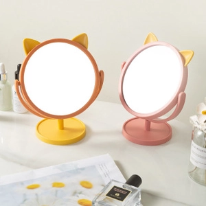 Detail of cat-ear desktop vanity mirrors in pink and yellow with adjustable base