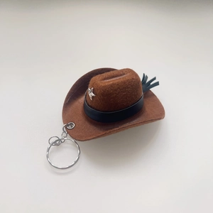 Brown felt cowboy hat keychain with black leather band and silver star on white background