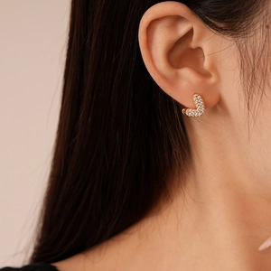 Close-up of gold plated heart-shaped earrings with micro-set cubic zirconia on earlobe