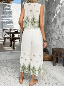 Back view of a white two-piece vacation set with green embroidery and wide-leg pants