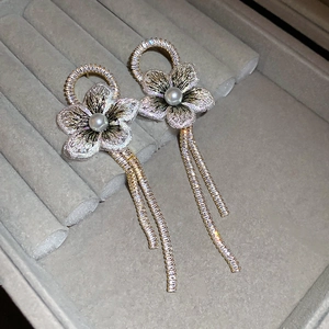 Détail macro des boucles d'oreilles fleurs en tulle avec perles et pompons zircon