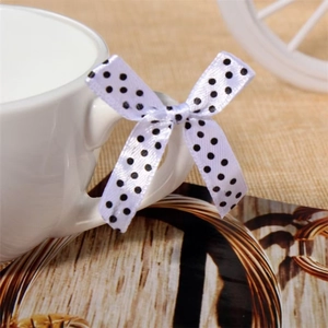 Macro shot of white satin ribbon bow with black polka dots on a ceramic cup handle