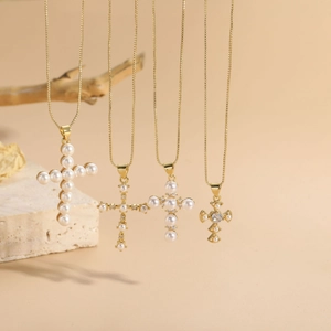Detail of four cross pendants with pearls and zircons on elegant stone and wood display