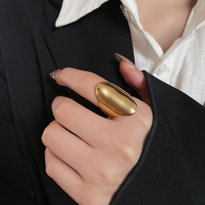 Polished gold oval ring detail on finger with a sleek minimalist metal surface finish