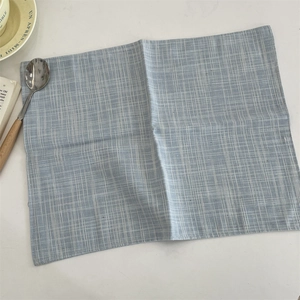 Detail of light blue plaid cotton linen placemat with textured weave and fine stitching