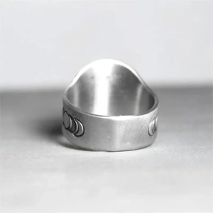 Close-up of matte silver ring showing engraved moon phases with vintage texture