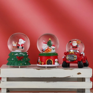 Three Christmas snow globes with Santa and snowman on a rustic white wooden box