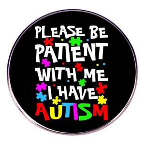 Detail view of round black autism awareness pin with Please Be Patient With Me lettering