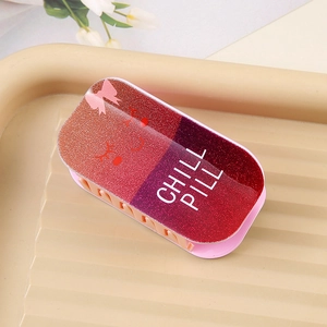 Detail of glitter capsule hair clip with Chill Pill text and red bow on beige tray