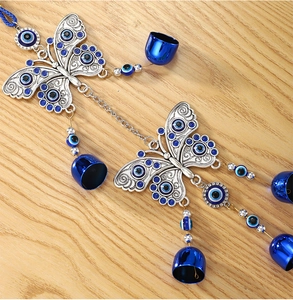 Detail view of silver metal butterfly wind chime with blue evil eye beads and small bells