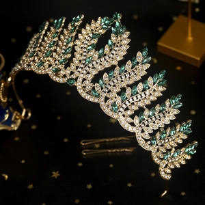 Detail of vintage baroque crown with green rhinestones and golden leaf patterns