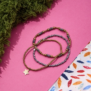 Three-piece layered beaded bracelet set with gold stars and metallic grey faceted beads