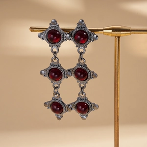 Detailed close-up of retro silver-tone earrings with three-tier round red resin gemstones