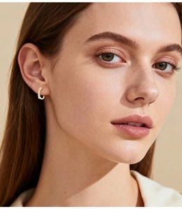 Detailed view of model wearing a minimalist gold-plated hoop earring with clear zircons