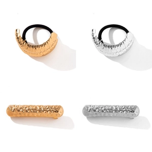 Golden and silver hammered metal elastic hair ties and geometric clips on white background