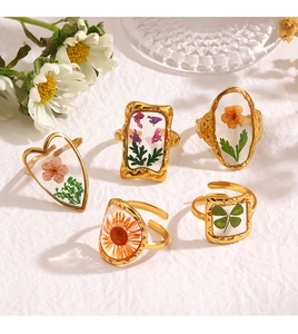 Detailed close-up of gold stainless steel rings with embedded dried flowers in resin