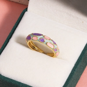 Détail de bagues en émail coloré finition dorée avec motifs à pois roses et bleus