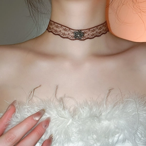 Detail view of a vintage brown lace choker featuring a heart flower with pearls and crystals