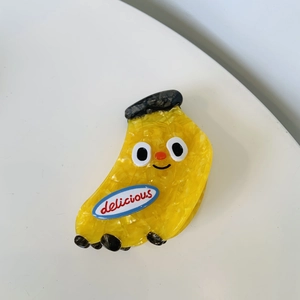 Detail of yellow banana hair claw clip with acetate texture and delicious lettering