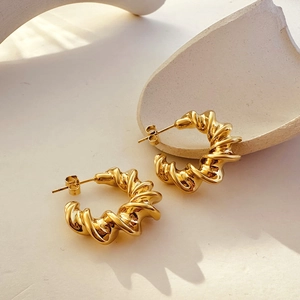 Macro detail of 18k gold plated croissant hoop earrings with a textured twist design