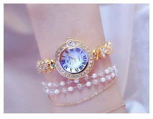 Detailed view of luxury gold women's watch with rhinestone dial and roman numerals