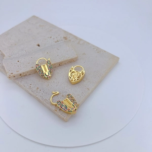 Dettaglio macro di fermagli a cuore placcati in oro con zirconi colorati e intagli