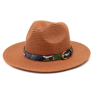 Close-up of brown straw fedora with colorful snake print band and gold buckle